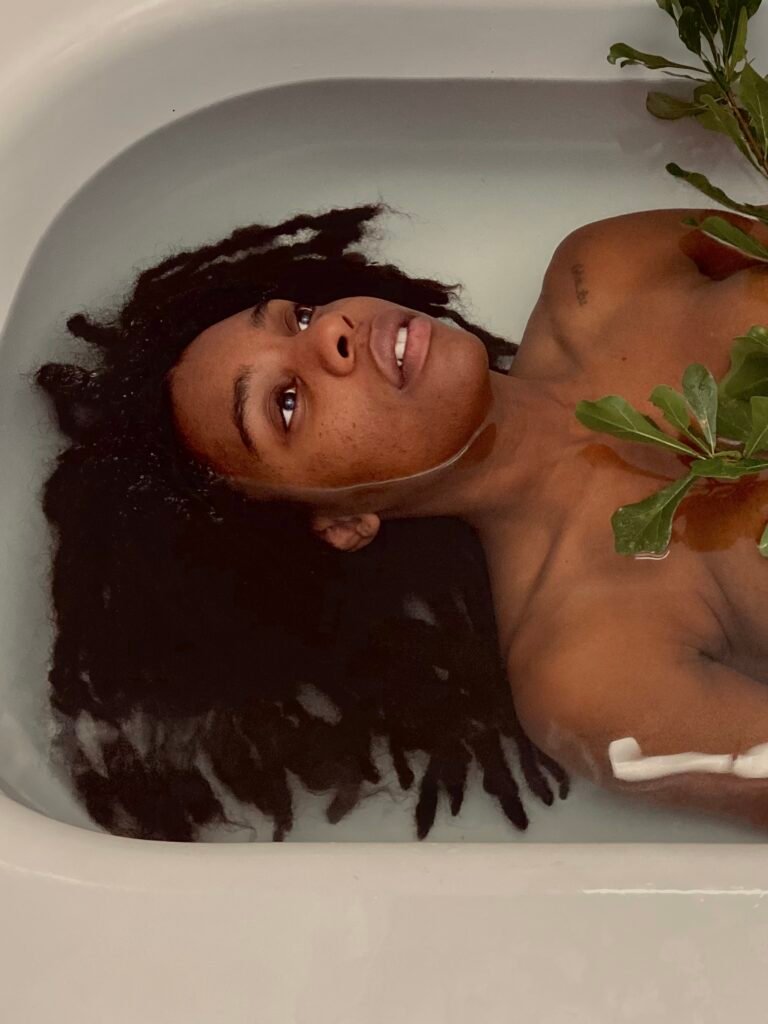 Black Woman With Natural Hair In Bathtub of Water Holding Oak Tree Stem